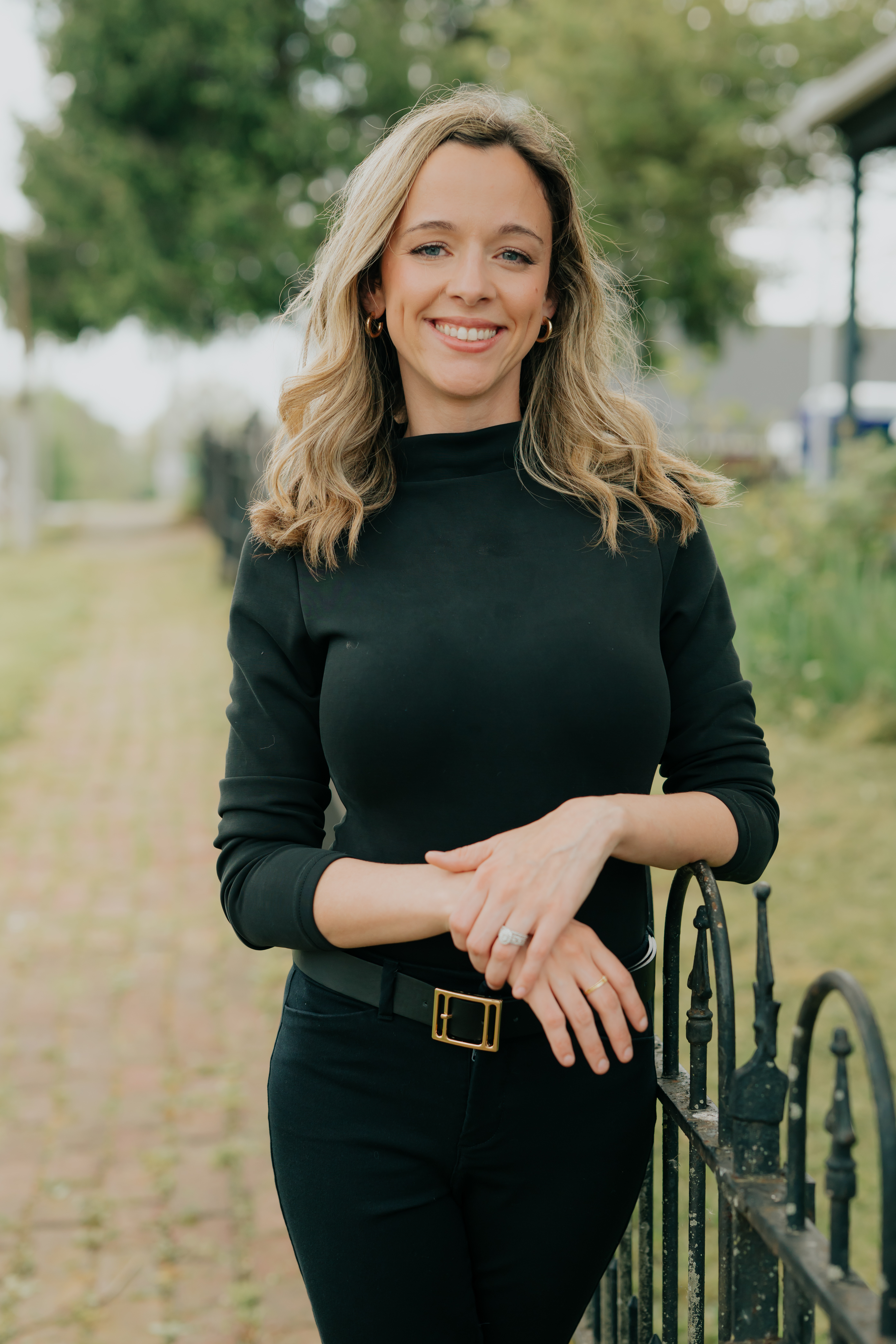 Hannah Keown, Central Kentucky REALTOR®, standing outdoors beside an iron gate